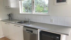 A modern kitchen with white cabinets, a stainless steel dishwasher, and a built-in microwave.