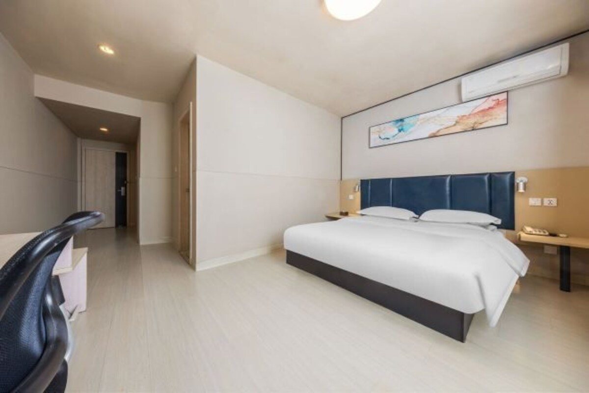 A modern hotel room with a large bed, a desk, and a chair.