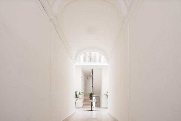 A hallway with a staircase leading to a landing, white walls, and a floor lamp.