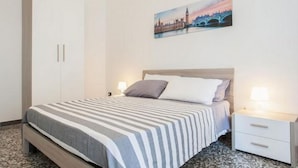 Ein Schlafzimmer mit einem Bett, Nachttischen, einem Gemälde und einem Kleiderschrank.