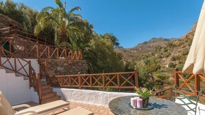 Una terraza con escaleras de piedra, sillones de descanso y una mesa con velas y flores.