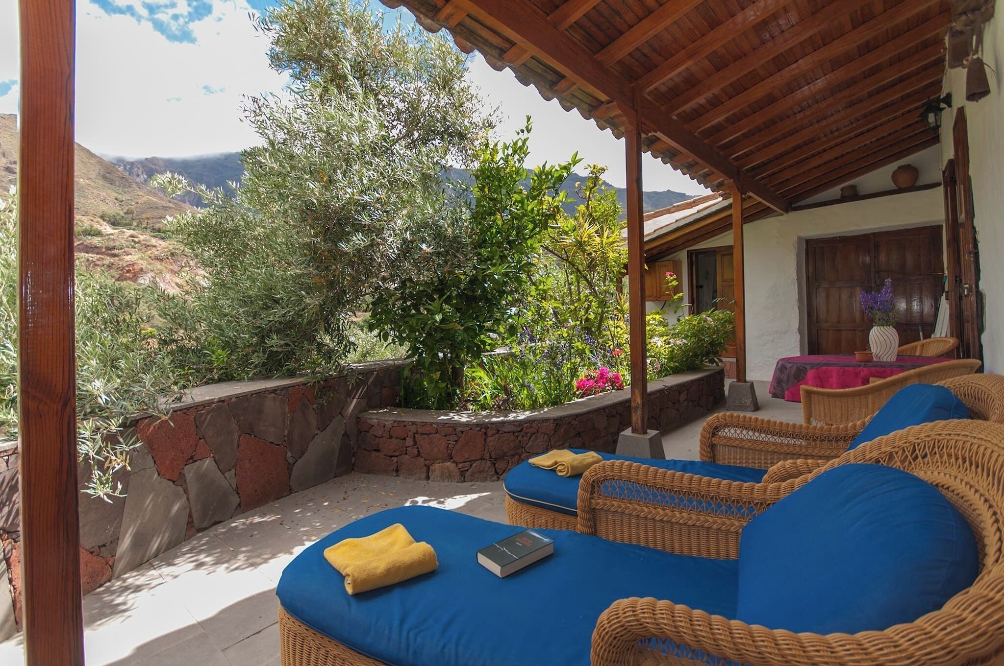 A covered outdoor seating area with wicker furniture and a view of the mountains.