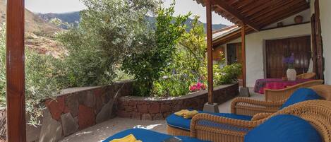 A covered outdoor seating area with wicker furniture and a view of the mountains.