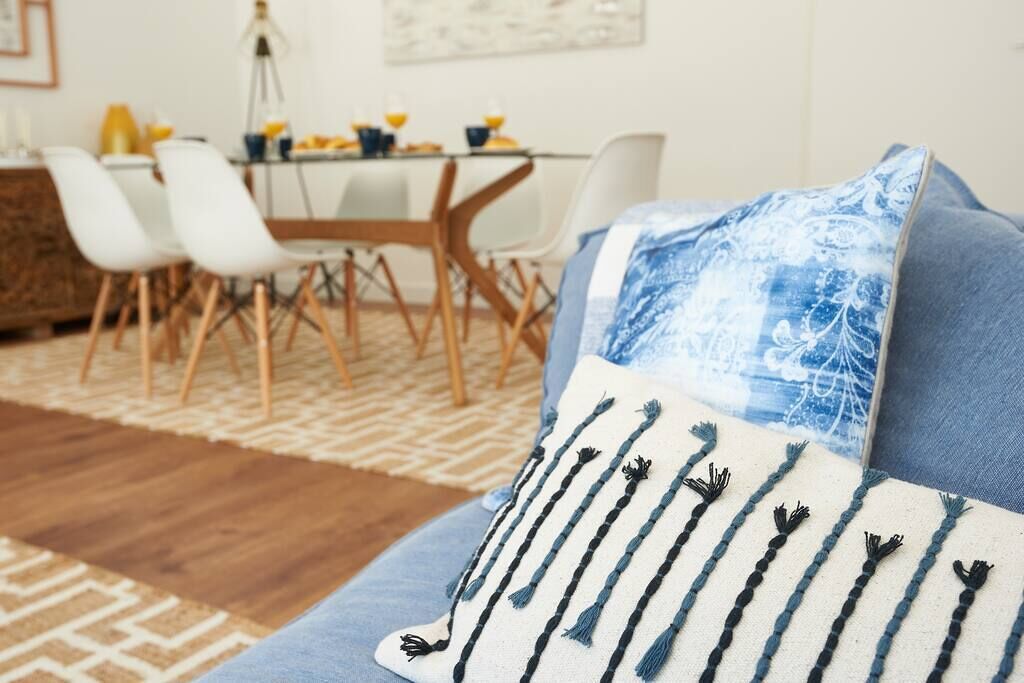 Ein modernes Wohnzimmer mit einer Couch, einem Kissen mit Muster und einem Essbereich mit Stühlen und einem Tisch.