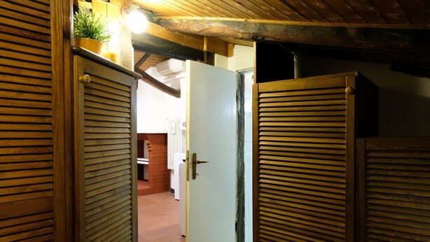 A wooden door with a latch, a potted plant on top, and a white door in the background.