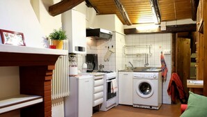 A compact kitchen with a washing machine, oven, and a small dining area.