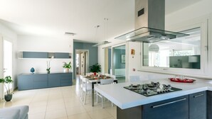 Una cocina moderna con una isla central, un comedor y vista al espacio de la sala.
