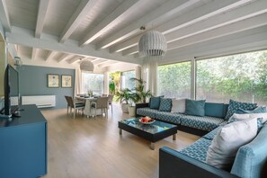 Una sala de estar moderna con comedor, ventanas amplias y techo con vigas a la vista.