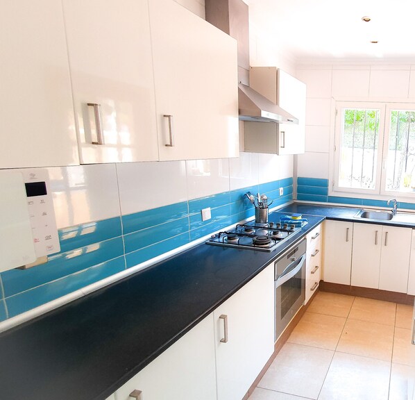 A kitchen with white cabinets, a black countertop, and blue tiles.