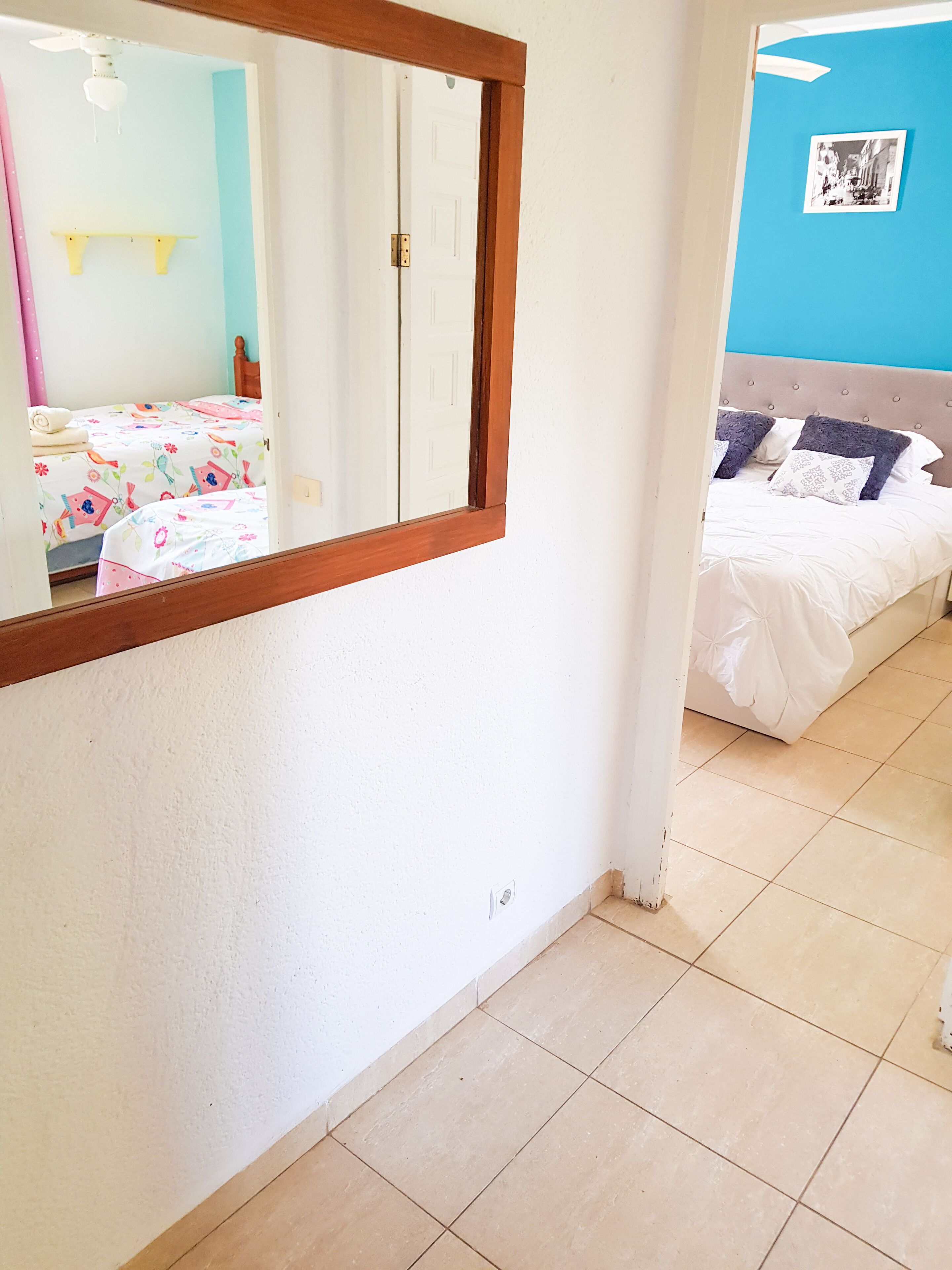 Une chambre à coucher avec un lit, un miroir et une porte donnant sur une autre pièce.