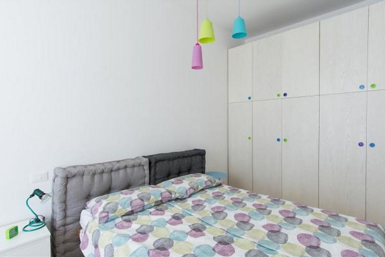 Een slaapkamer met een bed, een kledingkast en een bureau met een lamp.