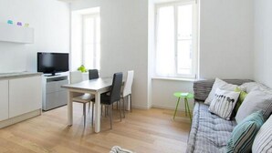 En moderne stue med spiseplads, sofa og fjernsyn.