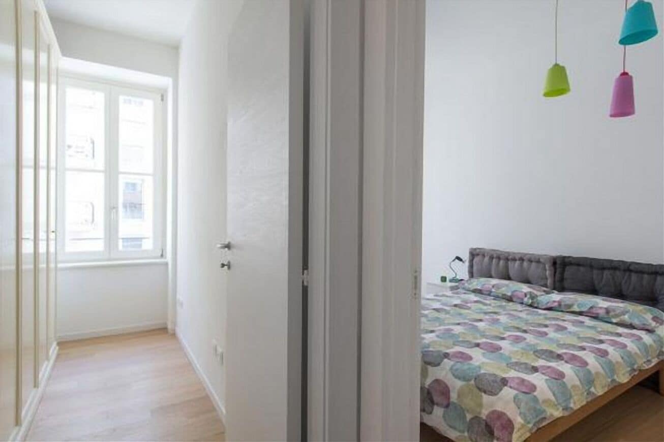 Een slaapkamer met een bed, een raam en een deur.