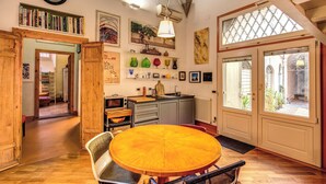 A cozy kitchen with wooden furniture, a dining table, and a view of the garden through the window.