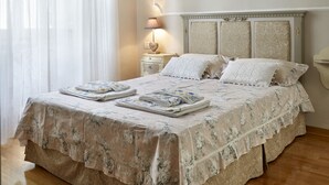 A neatly made bed with a floral bedspread, a bedside table with a lamp, and a window with sheer curtains. - The elegance in the heart of Florence (Firenze)