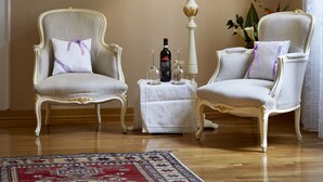 A room with two ornate chairs, a standing lamp, a floral painting on the wall, and a small table with a bottle and glass. - The elegance in the heart of Florence (Firenze)