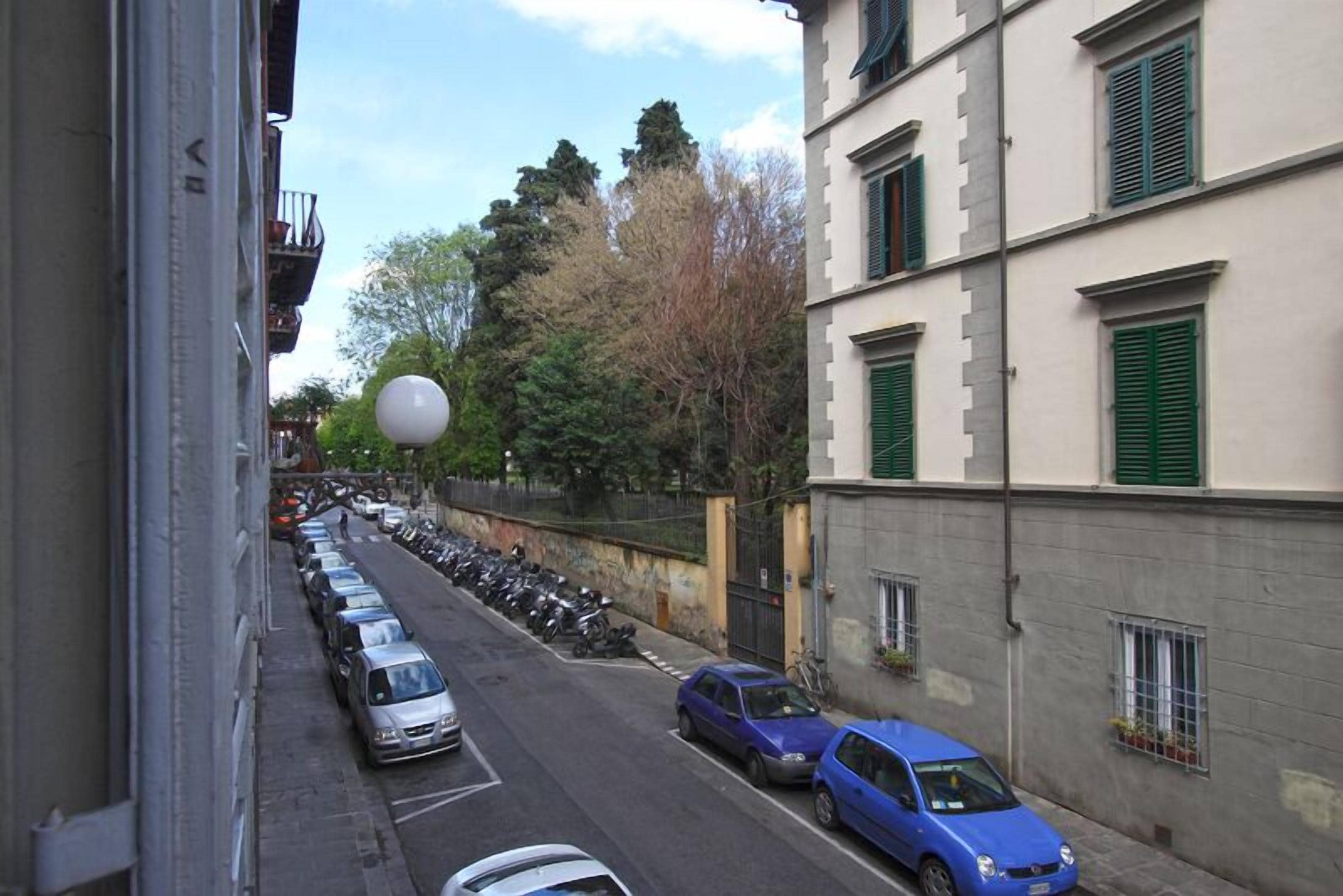 Une vue de rue avec des voitures garées et un bâtiment aux volets verts.