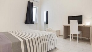 A hotel room with a bed, a desk, a chair, a television, and a window with curtains. - GuestHost - 13 NEW! 1bedroom & balcony P.zza Garibaldi! WiFi (Bari)