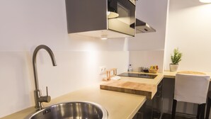Een moderne keuken met een RVS spoelbak, een houten aanrechtblad, een inbouwoven en een kleine plant in een pot.
