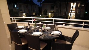 An outdoor dining area with a round table set for four, surrounded by wicker chairs.