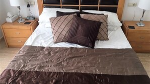 A neatly made bed with a brown quilt, two bedside tables with lamps, and a wooden headboard.