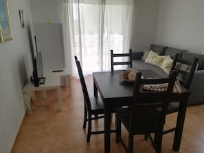 Ein Essbereich mit Tisch, Stühlen, einem Fernseher und einer Couch.