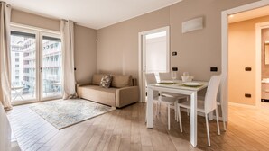 Un apartamento moderno con comedor, sofá y un amplio ventanal con cortinas.