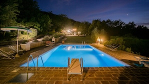 A rectangular swimming pool with a diving board and a lounge area with chairs and a table. - Two-storey villa with large private pool and beautiful landscaped garden (Castiglion Fiorentino)