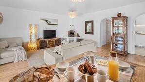 A modern living room with a fireplace, a dining table set with breakfast, and a cozy seating area. - House with heated swimming pool, solarium, large garden, high-speed WIFI access. (Lajares)