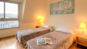 A bedroom with two beds, a window, and a painting of sailboats. - Nice apartment for 2 people with WIFI and TV (Trouville-sur-mer)