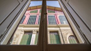 A view through a window of a building with multiple windows and a balcony.