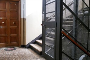 Eine Holztür, ein Metallgitter und eine Treppe, die zu einem Gebäude führt.