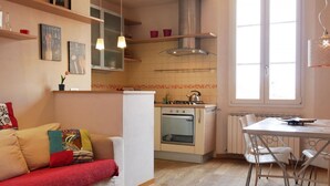 Una cucina compatta con piano cottura, forno e zona pranzo con sedie.