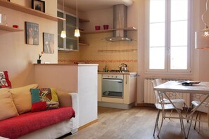 Une cuisine de taille réduite équipée d’une cuisinière, d’un four et d’un coin repas avec des chaises.