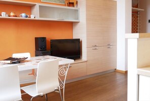 Cocina compacta con mesa, sillas, televisor y armarios.