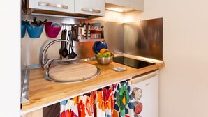 A kitchen with a stainless steel sink, wooden countertop, and a bowl of fruit.
