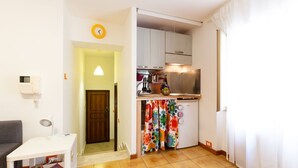 A compact kitchen with a refrigerator, stove, and cabinets. There is a small dining area with a table and a chair.