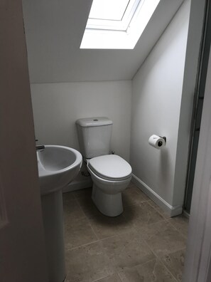 Bathroom features a toilet, pedestal sink, and tiled floor.