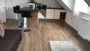 Kompakti keittiö, jossa on ruokailutila, pieni baarituoli ja puulattia.