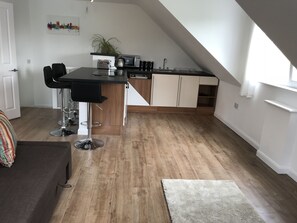 A compact kitchen with a dining area, a small bar stool, and a wooden floor. - Uskley Fairways. New, modern decor  (Cardiff)