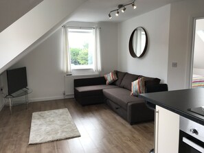 A modern living room with a sectional sofa, a flat-screen TV, and a dining area. - Uskley Fairways. New, modern decor  (Cardiff)