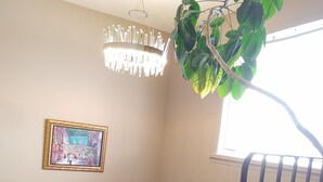 Una escalera con barandilla de metal, un candelabro, un cuadro en la pared y una planta en maceta.