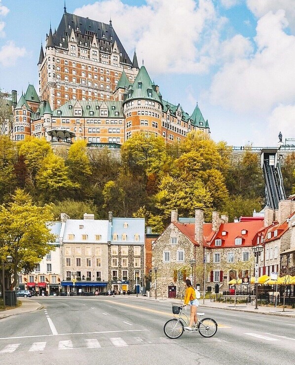 A historic building with a prominent tower and a cyclist on a street in front.