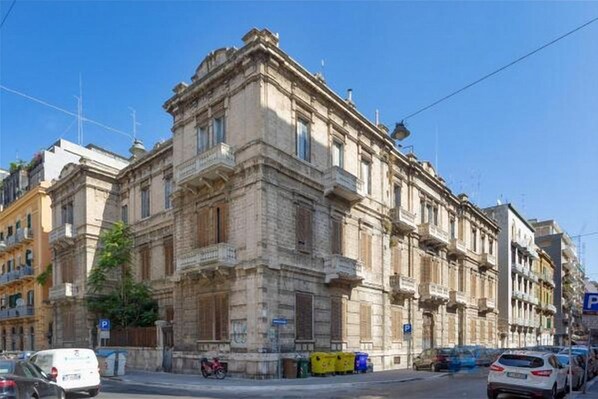 A historic building with classical architecture, a street view, and parked cars.