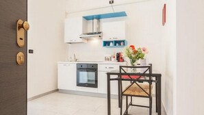 A compact kitchen with white cabinets, a black oven, and a blue-framed range hood. - GuestHost - 14. New Apartment perfect for 2! With Balcony! (Bari)