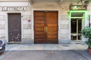 Un edificio con una porta di legno chiusa con l'etichetta 'ELETTRICITA' e un cartello con su scritto 'La Margherita' sopra una porta.