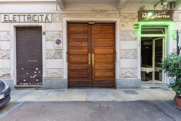 Un bâtiment avec une porte en bois fermée portant l’inscription « ELETTRICITA » et une enseigne « La Margherita » au-dessus d’un portail.