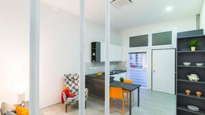 A modern kitchen with white cabinets, a dining table with two chairs, and a small island with a plant.