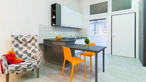 A compact kitchen with a dining area, a chair with a leaf pattern, and a table with two chairs.