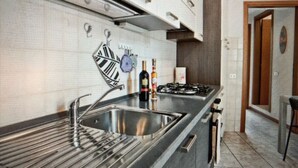 Een moderne keuken met een roestvrijstalen spoelbak, een gasfornuis en een betegelde spatwand.